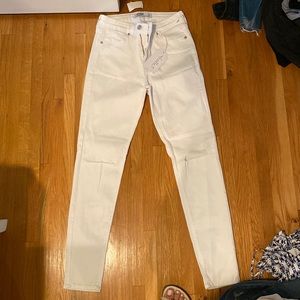 Skinny and Low-Rise white jeans with rips on either knee. New with tags!